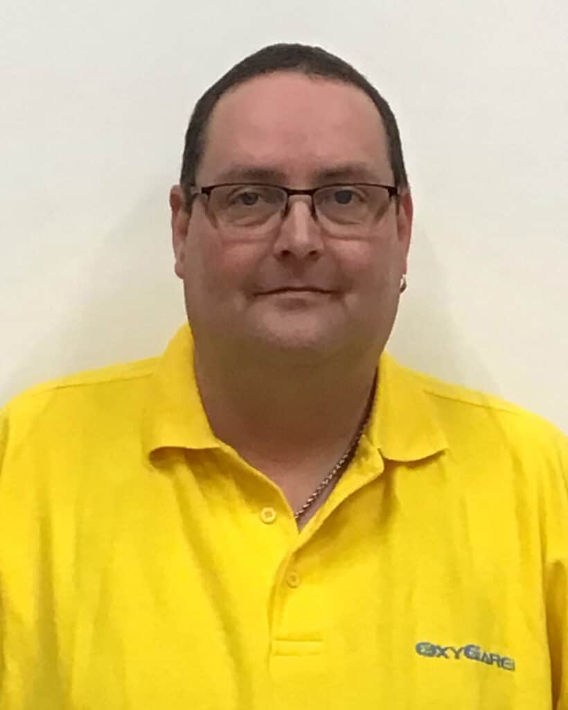 Foto von Jörg Burgard, Mitarbeiter von OxyCare. Er trägt ein gelbes Hemd mit dem OxyCare Logo und schaut freundlich in die Kamera.