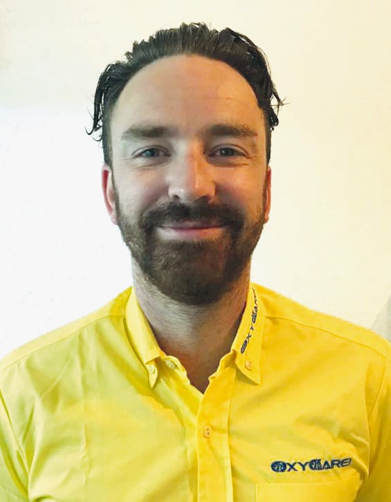 Foto von Steve Hargesheimer, Mitarbeiter von OxyCare. Er trägt ein gelbes Hemd mit dem OxyCare Logo und schaut freundlich in die Kamera.