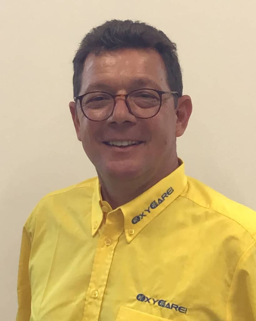 Foto von Matthias Oftring von Kannen, Mitarbeiter von OxyCare. Er trägt ein gelbes Hemd mit dem OxyCare Logo und schaut freundlich in die Kamera.