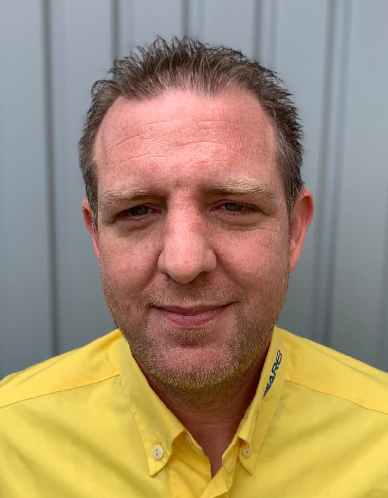 Foto von Tobias Rehborn, Mitarbeiter von OxyCare. Er trägt ein gelbes Hemd mit dem OxyCare Logo und schaut freundlich in die Kamera.