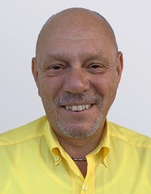 Foto von Roland Reif, Mitarbeiter von OxyCare. Er trägt ein gelbes Hemd mit dem OxyCare Logo und schaut freundlich in die Kamera.