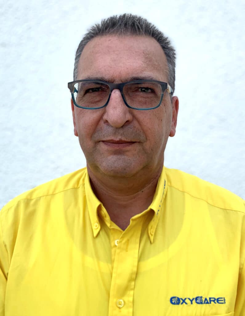 Foto von Torsten Schulz, Mitarbeiter von OxyCare. Er trägt ein gelbes Hemd mit dem OxyCare Logo und schaut freundlich in die Kamera.