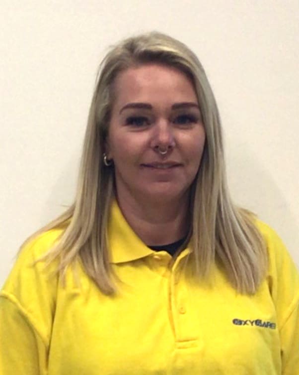Foto von Julia Werner, Mitarbeiterin von OxyCare. Sie trägt ein gelbes Hemd mit dem OxyCare Logo und schaut freundlich in die Kamera.