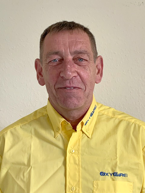 Foto von Steffen Dörre, Mitarbeiter von OxyCare. Er trägt ein gelbes Hemd mit dem OxyCare Logo und schaut freundlich in die Kamera.