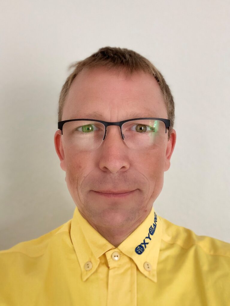 Foto von Robert Schaal, Mitarbeiter von OxyCare. Er trägt ein gelbes Hemd mit dem OxyCare Logo und schaut freundlich in die Kamera.