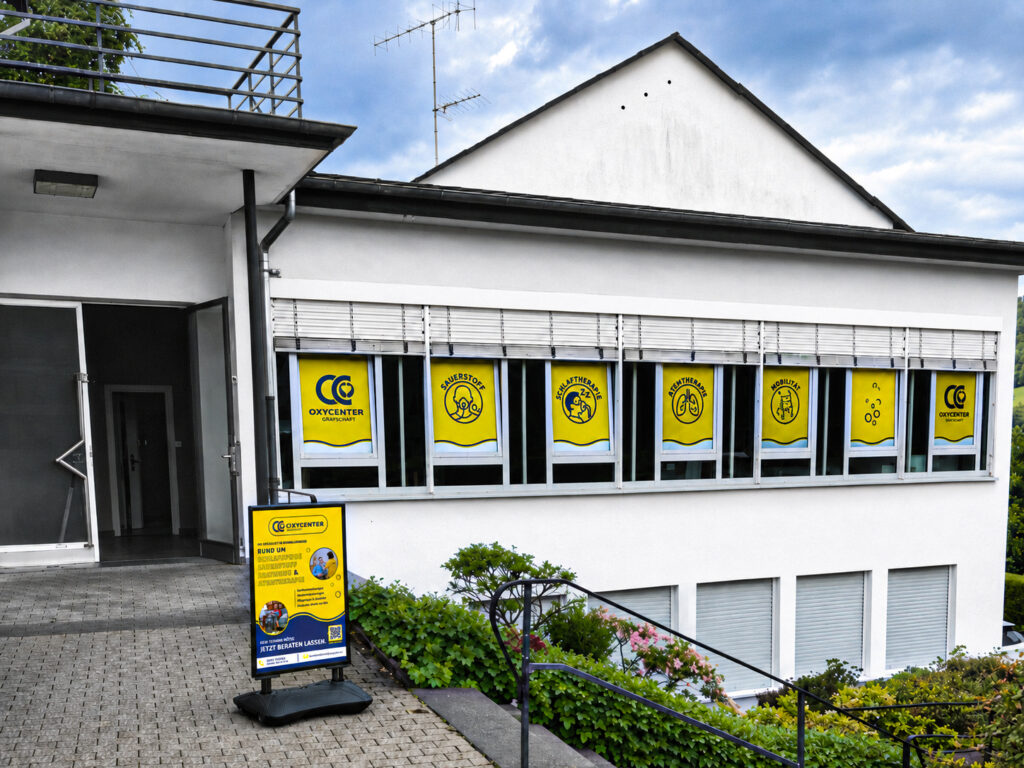 Außenansicht des OxyCenter Grafschaft in Schmallenberg mit Fensterbeklebung und Aufsteller vor dem Eingang